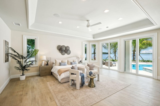 bedroom with a tray ceiling, access to exterior, and light wood-type flooring