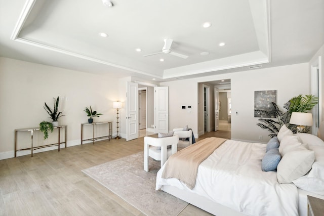 bedroom with ceiling fan, a raised ceiling, and light wood-type flooring