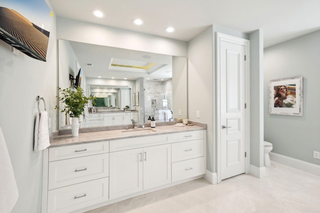 bathroom featuring vanity, toilet, a shower with door, and a tray ceiling