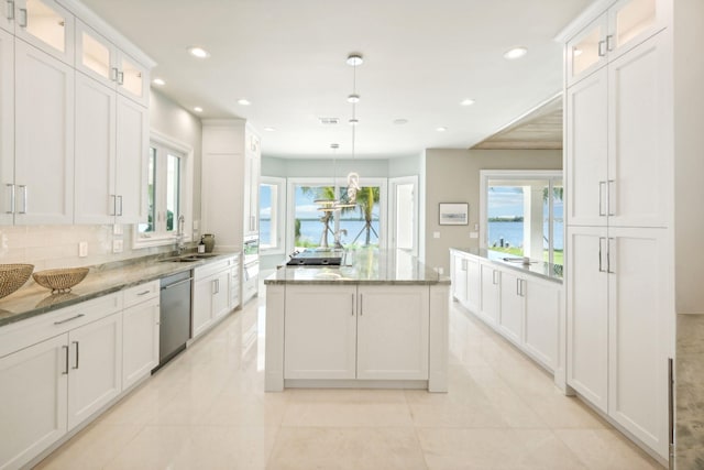 kitchen featuring stainless steel appliances, light stone countertops, pendant lighting, and white cabinets