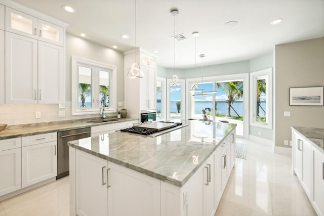 kitchen featuring a kitchen island, appliances with stainless steel finishes, white cabinetry, sink, and hanging light fixtures