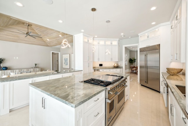 kitchen with high end appliances, light stone countertops, white cabinets, a kitchen island, and decorative light fixtures