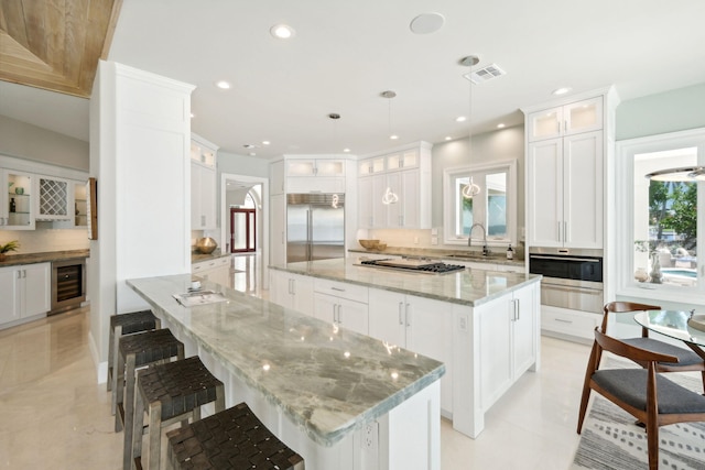 kitchen with pendant lighting, sink, stainless steel appliances, a center island, and wine cooler