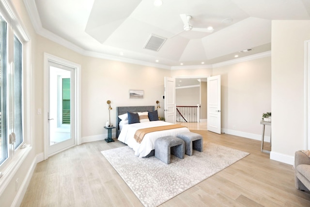 bedroom with a raised ceiling, crown molding, and light wood-type flooring