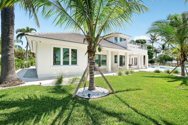 back of house with a lawn, a patio, and a balcony