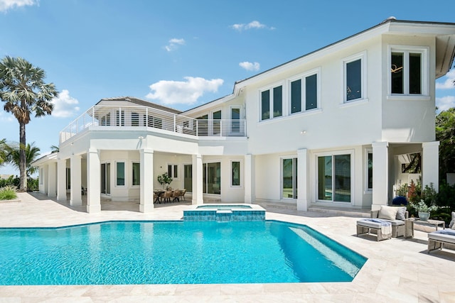 back of property featuring a balcony, a pool with hot tub, and a patio