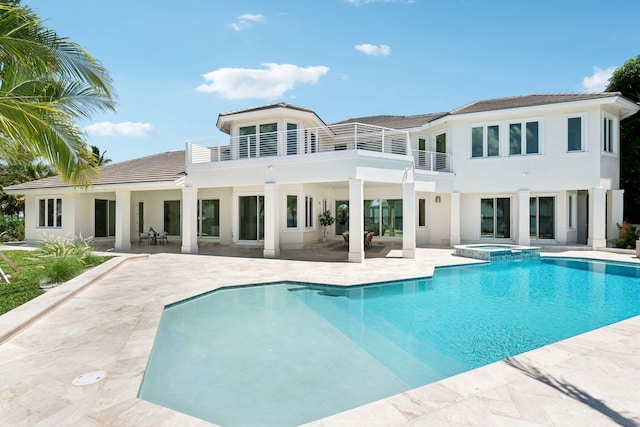 back of house featuring a balcony, a swimming pool with hot tub, and a patio area