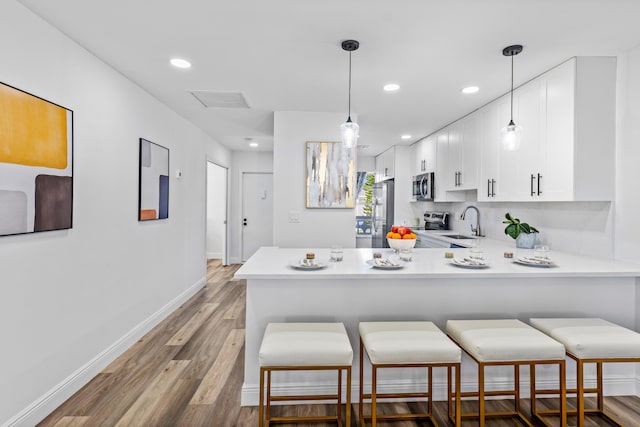 2825 SW 13th St Unit 204, Delray Beach, FL 33445 - kitchen featuring stainless steel appliances, a sink, a peninsula, light countertops, and white cabinetry