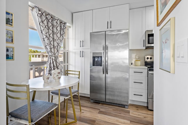 kitchen with stainless steel appliances, light wood-type flooring, and white cabinets