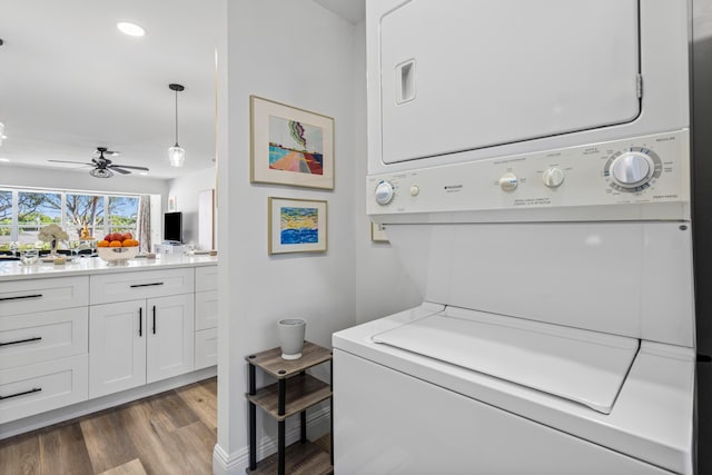 laundry room with ceiling fan, stacked washing maching and dryer, and dark hardwood / wood-style flooring