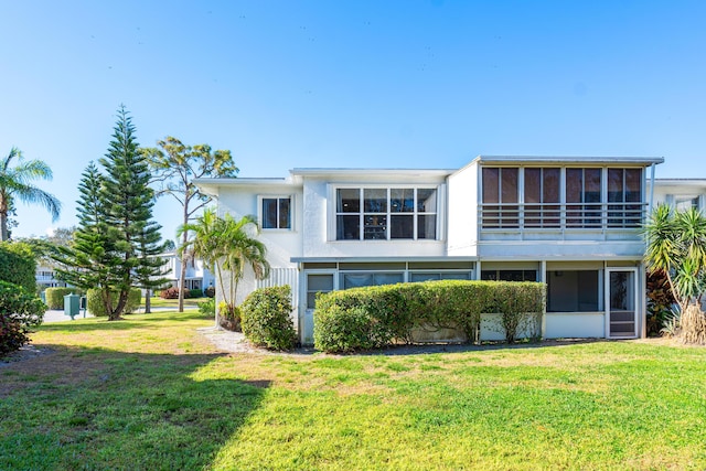 back of property with a sunroom and a yard