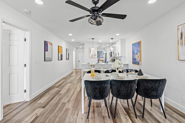 kitchen with sink, light hardwood / wood-style flooring, appliances with stainless steel finishes, pendant lighting, and white cabinets