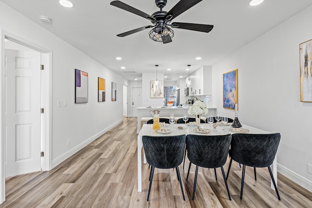 dining space with ceiling fan and light wood-type flooring