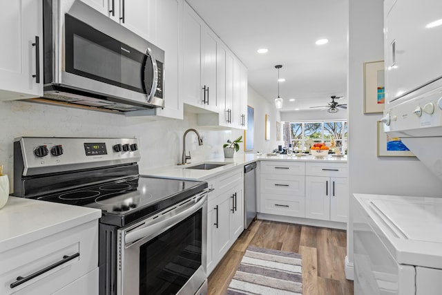 kitchen featuring sink, ceiling fan, appliances with stainless steel finishes, white cabinetry, and hardwood / wood-style floors