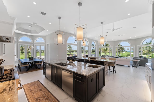 kitchen with decorative light fixtures, light stone countertops, sink, and dishwasher