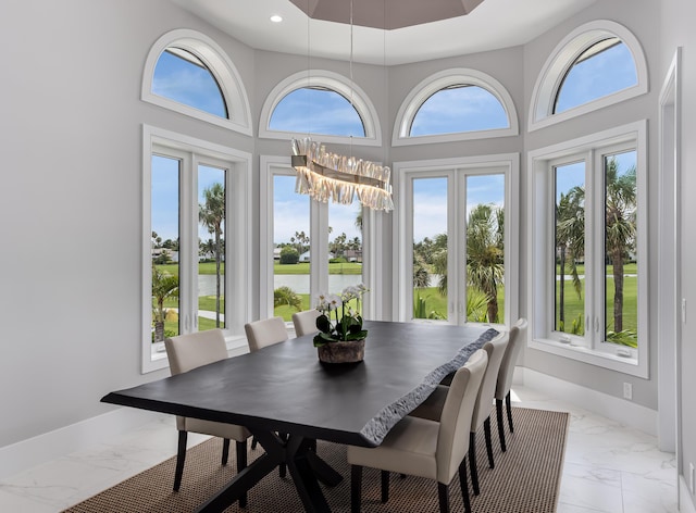 sunroom featuring a chandelier and a water view