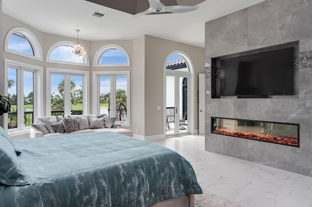 bedroom featuring french doors, a multi sided fireplace, ceiling fan with notable chandelier, and access to outside