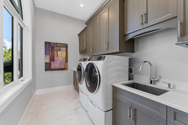 laundry room featuring sink, washer and clothes dryer, and cabinets