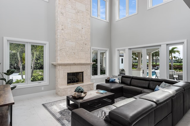 living room with a stone fireplace, french doors, and a high ceiling