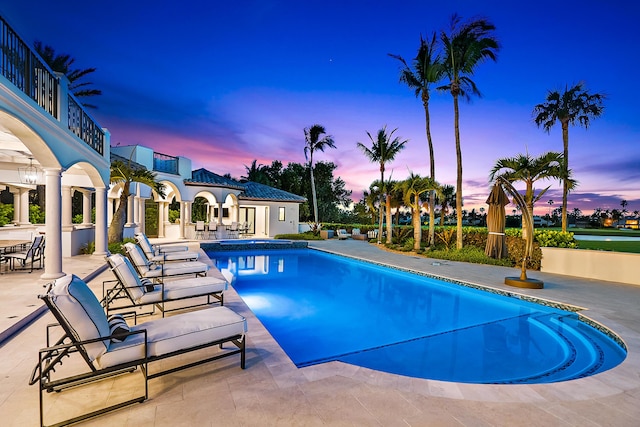 pool at dusk with a patio area