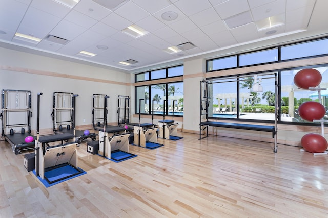 exercise room featuring a towering ceiling, a paneled ceiling, and light hardwood / wood-style floors