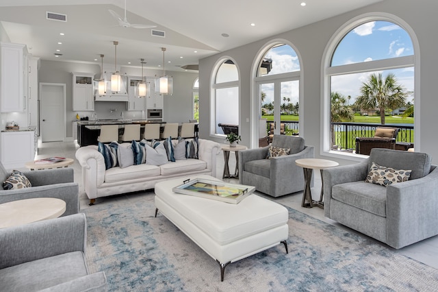 living room with ceiling fan, plenty of natural light, and vaulted ceiling