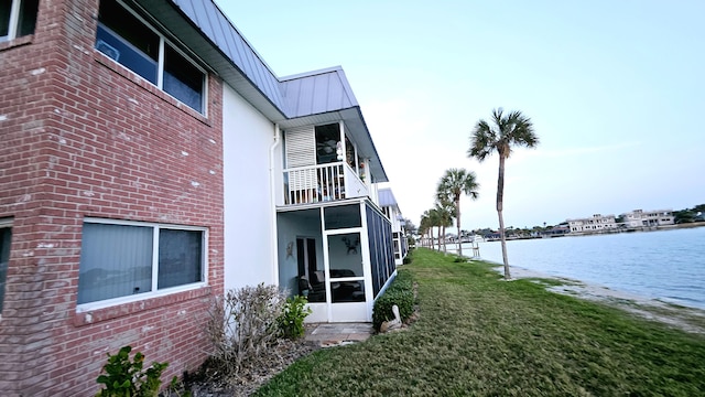 view of property exterior with a water view and a lawn