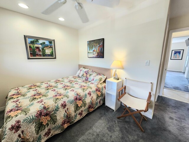 bedroom with ceiling fan, dark carpet, and multiple windows