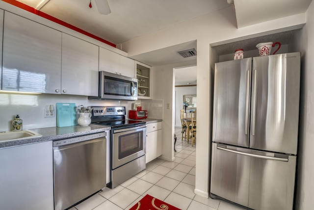 kitchen with light tile patterned floors, sink, ceiling fan, appliances with stainless steel finishes, and white cabinetry