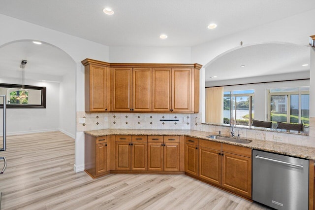 kitchen with dishwasher, sink, backsplash, and light stone counters