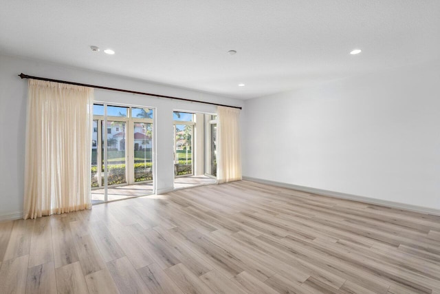 unfurnished room with a textured ceiling and light wood-type flooring