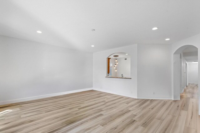 unfurnished living room featuring a textured ceiling and light wood-type flooring