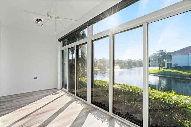 unfurnished sunroom with ceiling fan and a water view