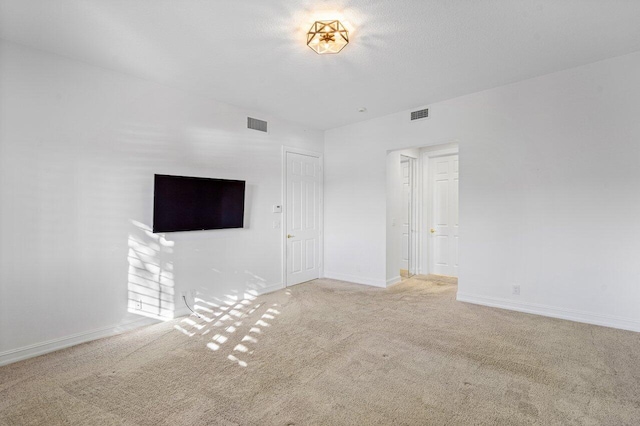 unfurnished living room featuring a textured ceiling, carpet floors, visible vents, and baseboards