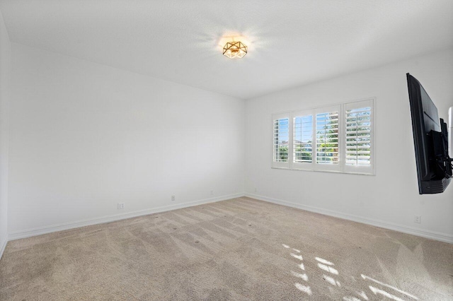 empty room with light carpet, baseboards, and a textured ceiling