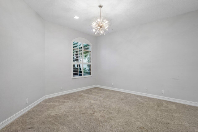 empty room featuring a notable chandelier and carpet floors