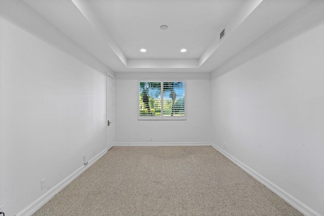 empty room with recessed lighting, light colored carpet, visible vents, baseboards, and a tray ceiling