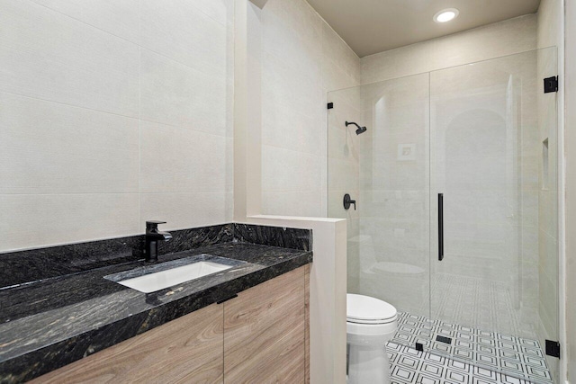 bathroom with a stall shower, vanity, toilet, and tile patterned floors