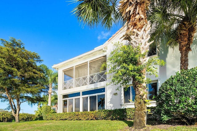 back of property with a lawn and stucco siding