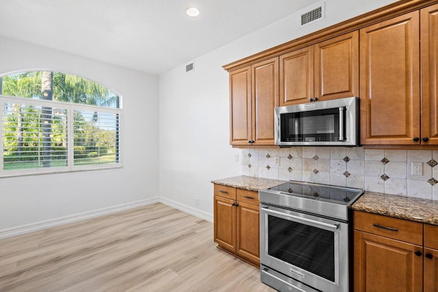 kitchen with light stone counters, stainless steel appliances, and decorative backsplash