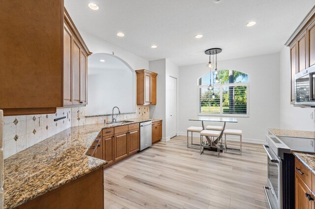 kitchen with light stone countertops, stainless steel appliances, and light wood-type flooring