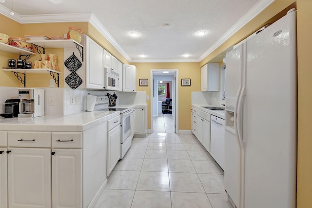 kitchen with tile countertops, white cabinetry, ornamental molding, light tile patterned floors, and white appliances