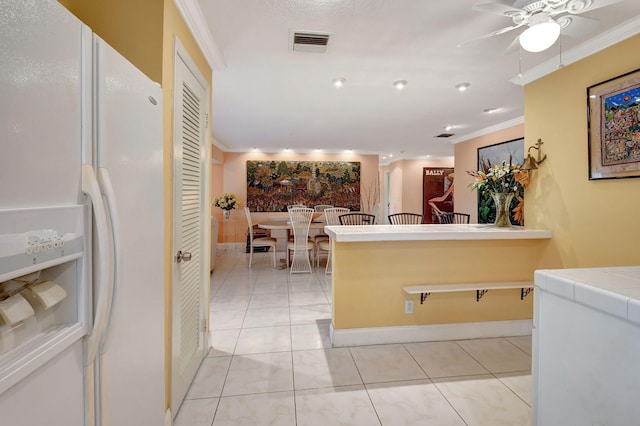 kitchen featuring light tile patterned flooring, ornamental molding, tile countertops, and white fridge with ice dispenser