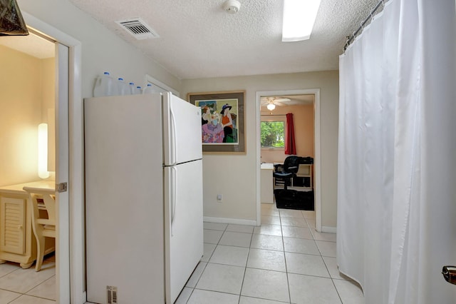 hallway with a textured ceiling and light tile patterned flooring