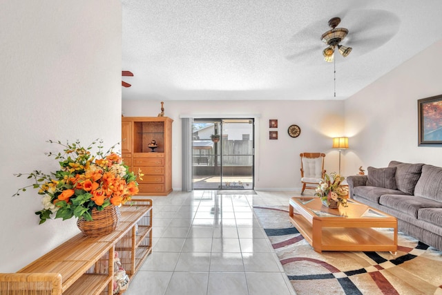 living room with light tile patterned floors, baseboards, a textured ceiling, and a ceiling fan