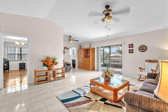 living area featuring light tile patterned floors, ceiling fan with notable chandelier, a textured ceiling, and vaulted ceiling