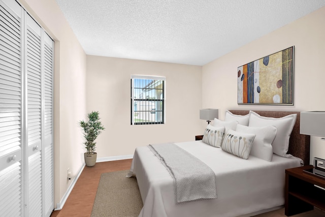 bedroom featuring a closet, a textured ceiling, baseboards, and wood finished floors