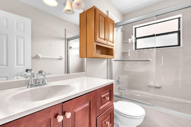 bathroom featuring enclosed tub / shower combo, toilet, and vanity