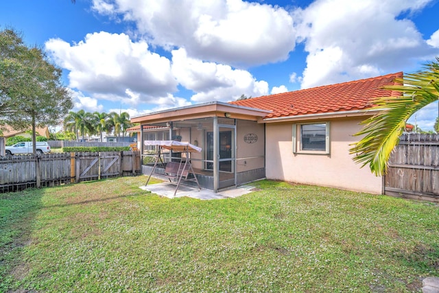 back of house featuring a tile roof, a sunroom, stucco siding, a fenced backyard, and a yard