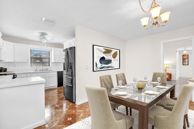 dining room with visible vents, baseboards, a textured ceiling, and an inviting chandelier